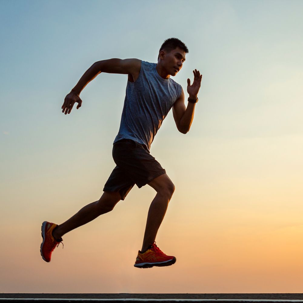 Man sprinting outdoors at sunset for fitness and endurance support